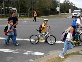 Picture of a kid walking his bike in a crosswalk